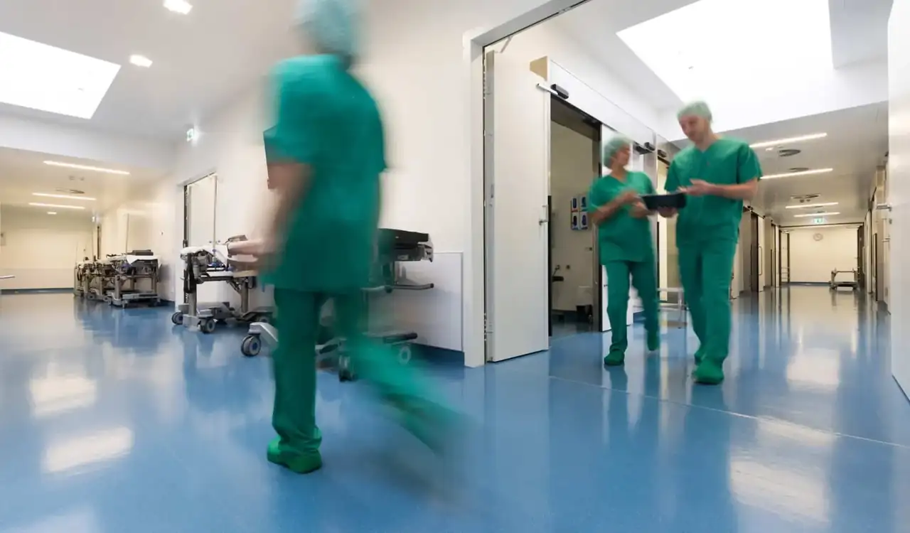 Mitarbeitende in medizinischer Berufsbekleidung im Klinikflur